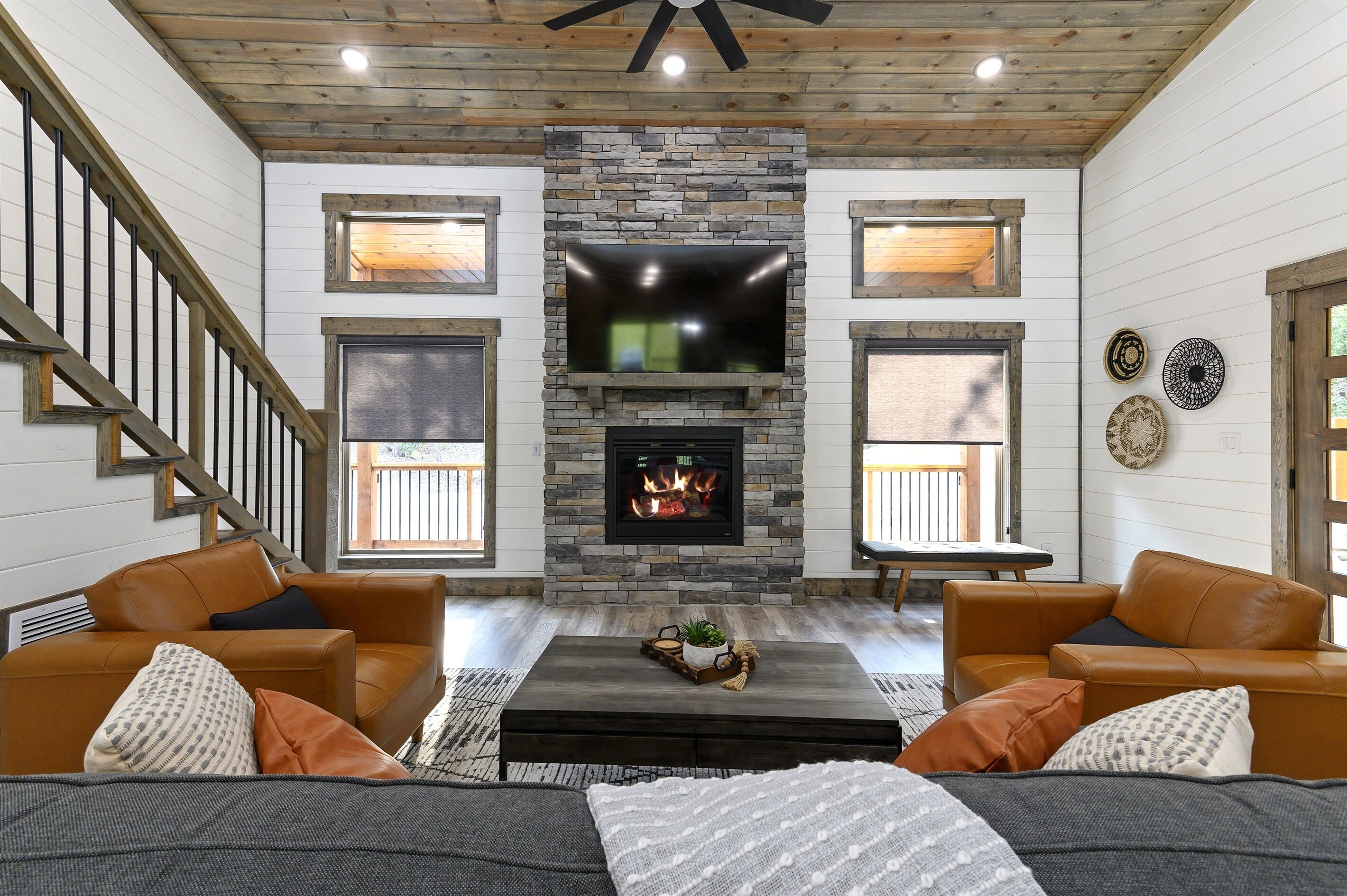 Una sala de estar con chimenea de piedra, sofás de cuero y televisor de pantalla plana.
