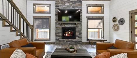 Una sala de estar con chimenea de piedra, sofás de cuero y televisor de pantalla plana.