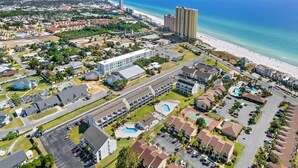 Vista aèria d'una zona de platja amb edificis davant del mar, un gran complex hotelier i una piscina.