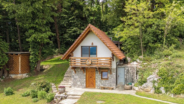 A stone house with a wooden balcony, a wooden door, and a small window. - Vineyard Cottages Rataj (Novo Mesto)