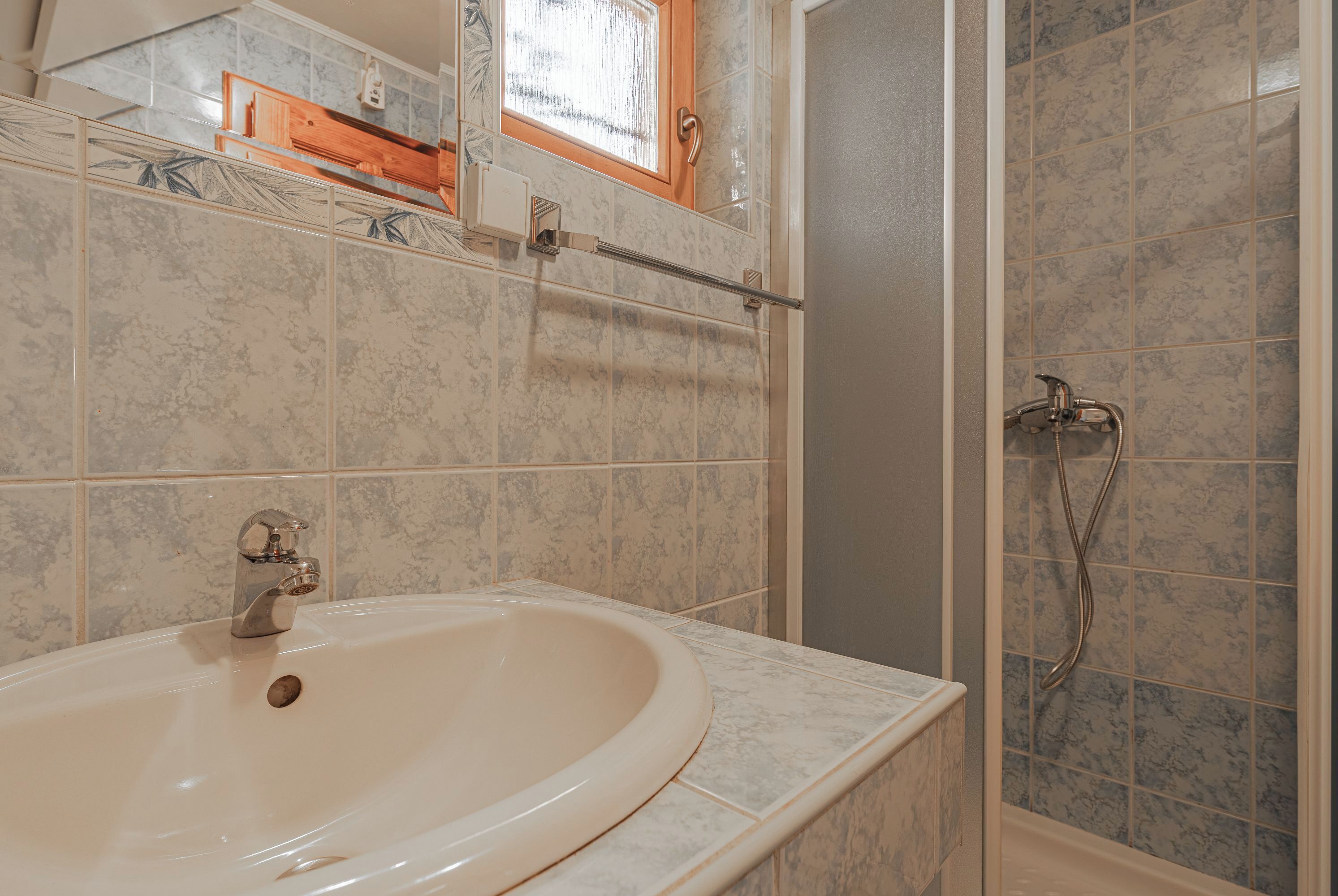 Un bagno con lavandino, doccia e finestra.