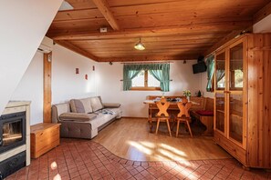 Une pièce chaleureuse avec un plafond en bois, un canapé, une table à manger avec des chaises, un buffet et une cheminée.