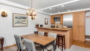 Uma cozinha moderna com ilha de madeira, eletrodomésticos de aço inoxidável e um lustre.