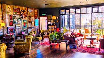 A spacious room with wooden flooring, a large window, and various pieces of furniture including chairs, a sofa, and a table.