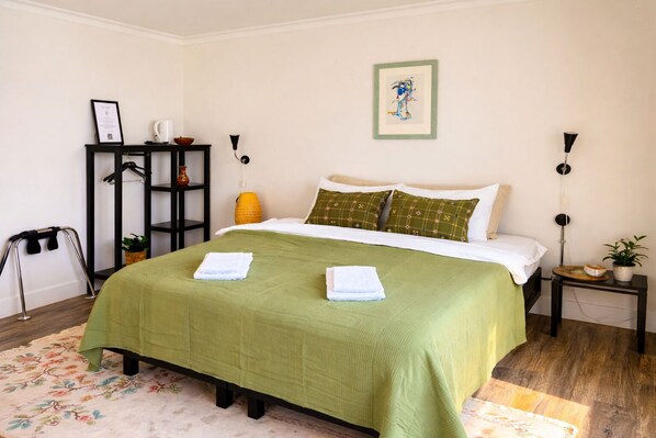 A neatly arranged bedroom with a bed, a side table, a wall-mounted shelf, and a framed picture on the wall. - Hotel Brú countryside (Selfoss)