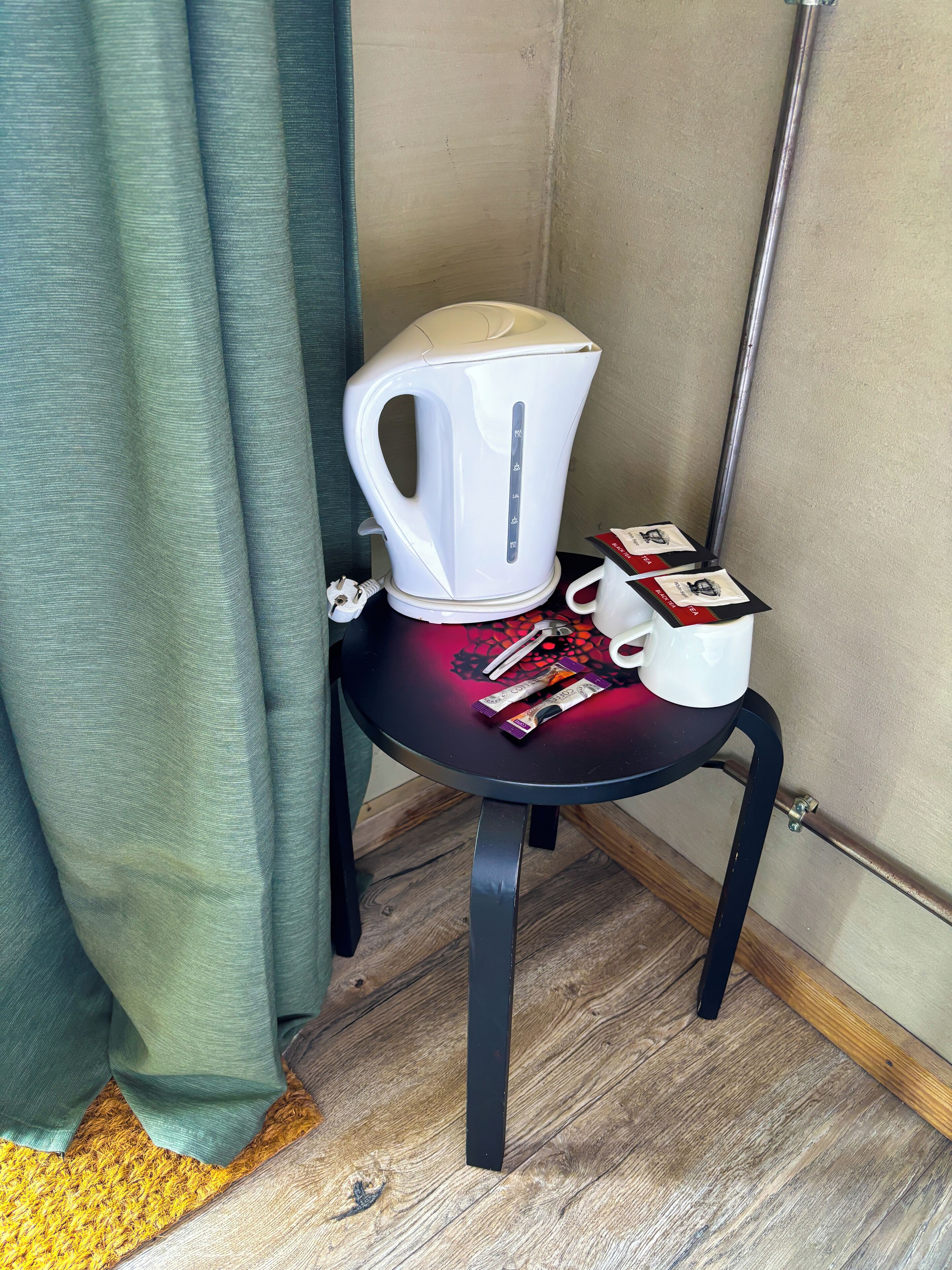 Un tavolino con un bollitore elettrico bianco, una tazza bianca e una confezione di tè.