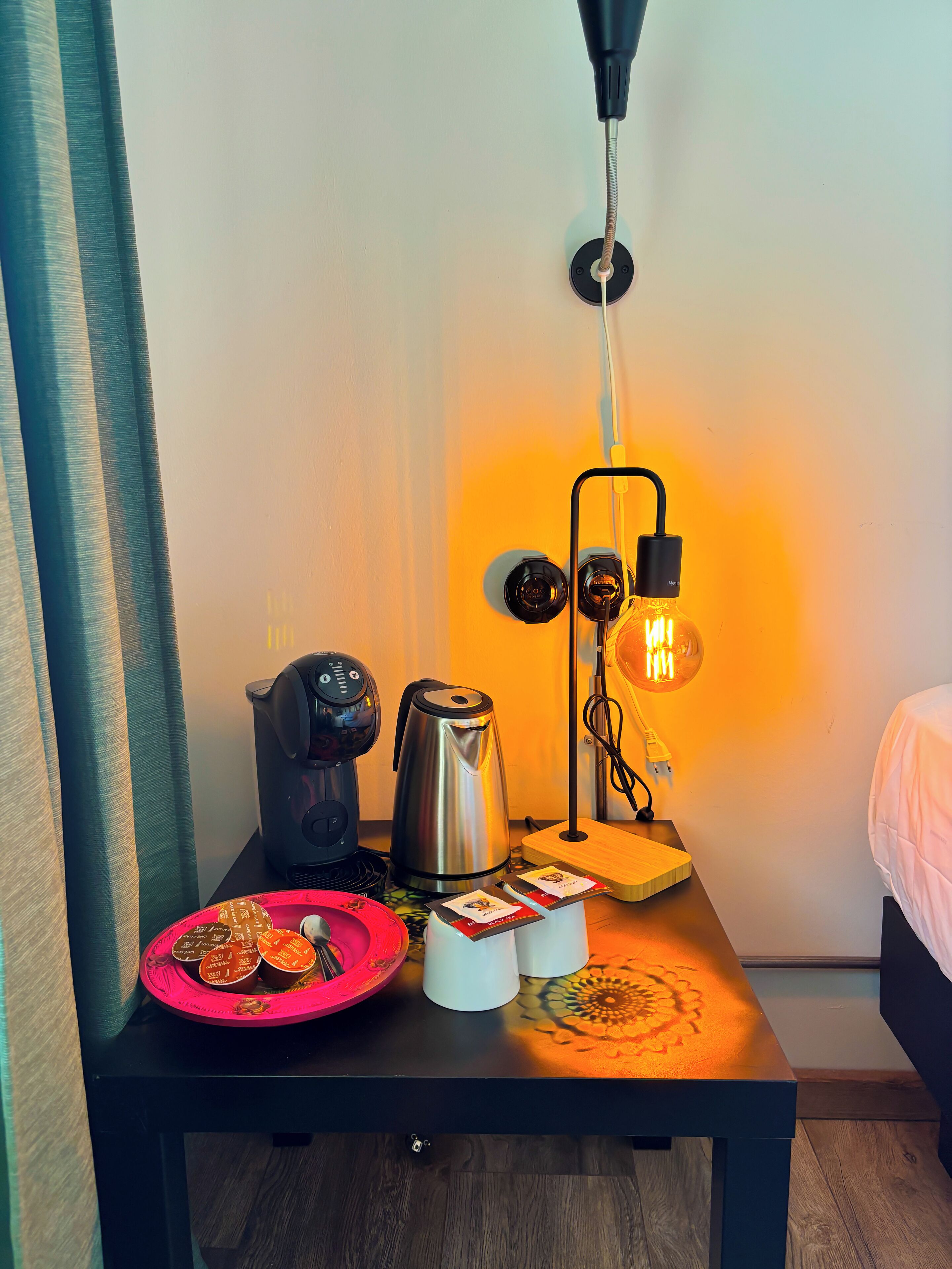 Een keurig opgemaakte tafel met een waterkoker, een koffiezetapparaat en een lamp.