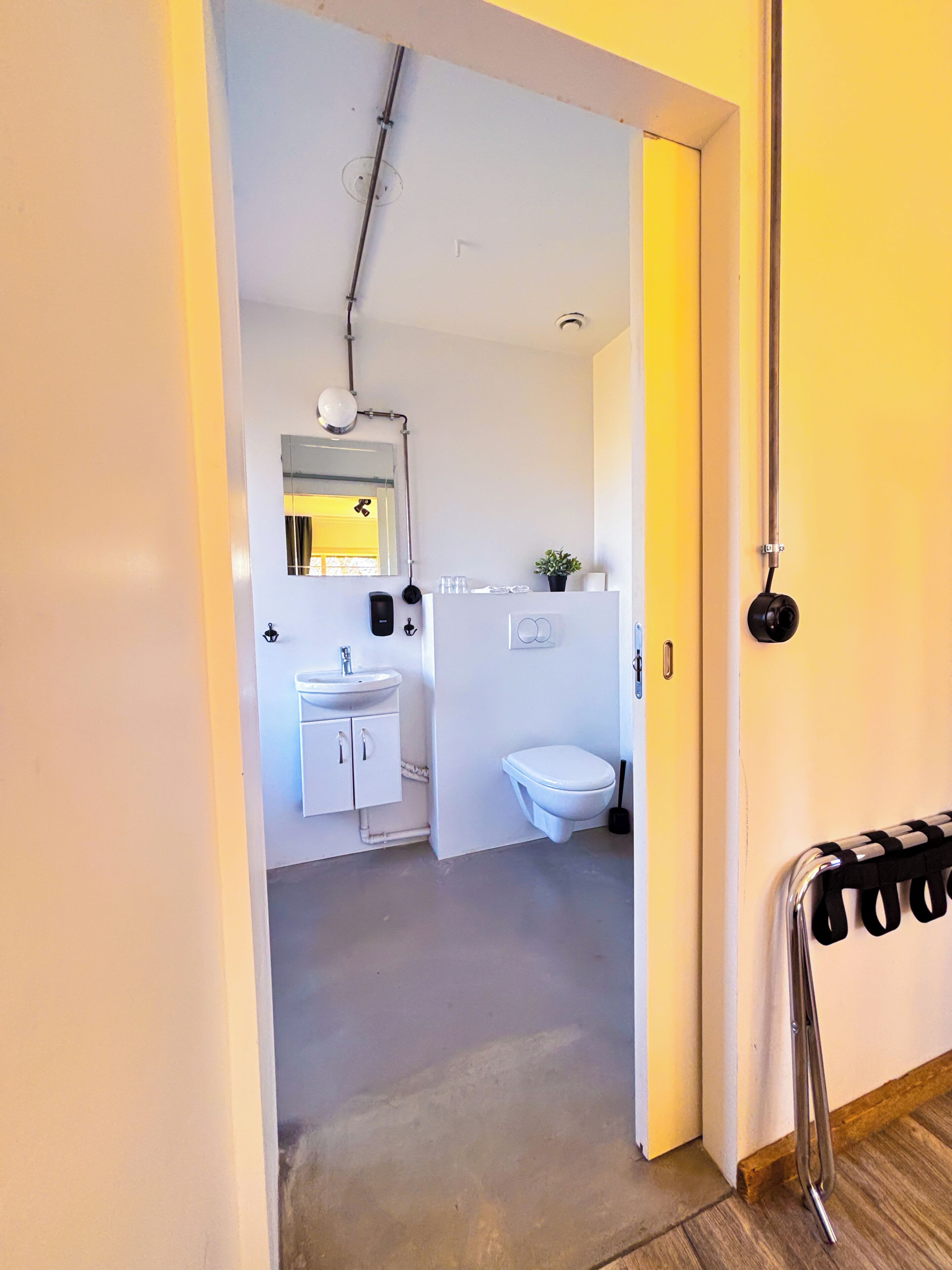 A modern bathroom with a white sink, mirror, and toilet.