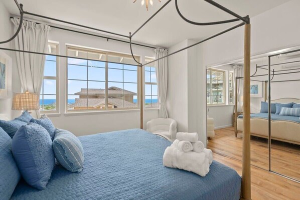 Un dormitorio con una cama grande, una silla, un armario y vista al mar.