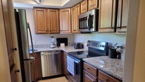 A kitchen with wooden cabinets, stainless steel appliances, a granite countertop, and a tiled floor. - Perfect 2nd floor condo with mtn & golf  views! Charm galore awaits you! (Tucson)
