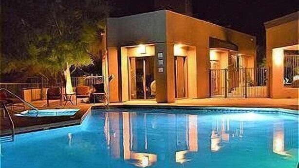 A swimming pool with a lounge area, a covered seating area, and a building with doors and windows. - Perfect 2nd floor condo with mtn & golf  views! Charm galore awaits you! (Tucson)