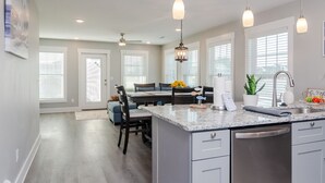 A modern kitchen with granite countertops, stainless steel appliances, pendant lighting, and a central island. - Brand New Construction short walk to the beach! (Carolina Beach)