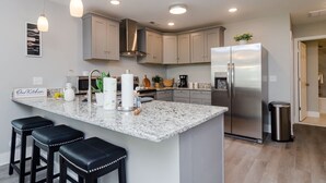 A modern kitchen with a large island, stainless steel appliances, and a clean, minimalist design. - Brand New Construction short walk to the beach! (Carolina Beach)