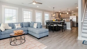 A modern living room with a sectional sofa, dining area, and kitchen. - Brand New Construction short walk to the beach! (Carolina Beach)