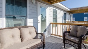 A covered porch with wicker furniture and a wooden railing. - Brand New Construction short walk to the beach! (Carolina Beach)