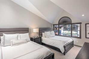 Ein Schlafzimmer mit zwei Betten, einem Nachttisch, einer Lampe und einem Fenster mit Blick.