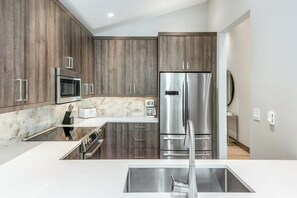 Une cuisine moderne avec des meubles en bois, des appareils en acier inoxydable et un pare-feu en marbre.