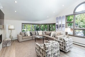 Een moderne woonkamer met een hoekbank, twee fauteuils, een salontafel en een open haard.