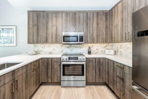 Une cuisine moderne avec des meubles en bois, un four en acier inoxydable, un four à micro-ondes et un réfrigérateur.