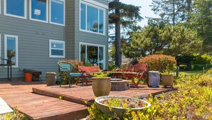Une terrasse dotée de mobilier d’extérieur, d’un jardinière en pierre et d’une maison avec de grandes fenêtres.