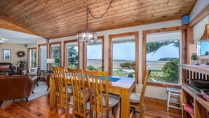 Un coin repas en bois avec vue sur la mer, un plafond en bois et une cheminée.