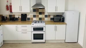 A kitchen with white cabinets, a gas stove, a microwave, and a refrigerator. - Impeccable 3 bed House in Brentwood (Brentwood)