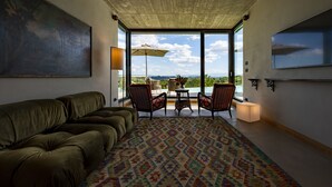 A modern living room with a large sofa, a patterned rug, and a dining area with chairs and a table. - Relais Casa Clara (Monteu Roero)
