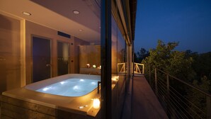 A modern bathroom with a large bathtub, a shower area, and a glass-enclosed balcony with a railing. - Relais Casa Clara (Monteu Roero)