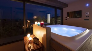 A modern bathroom with a large bathtub, a wooden vanity, and a window overlooking a cityscape at night. - Relais Casa Clara (Monteu Roero)