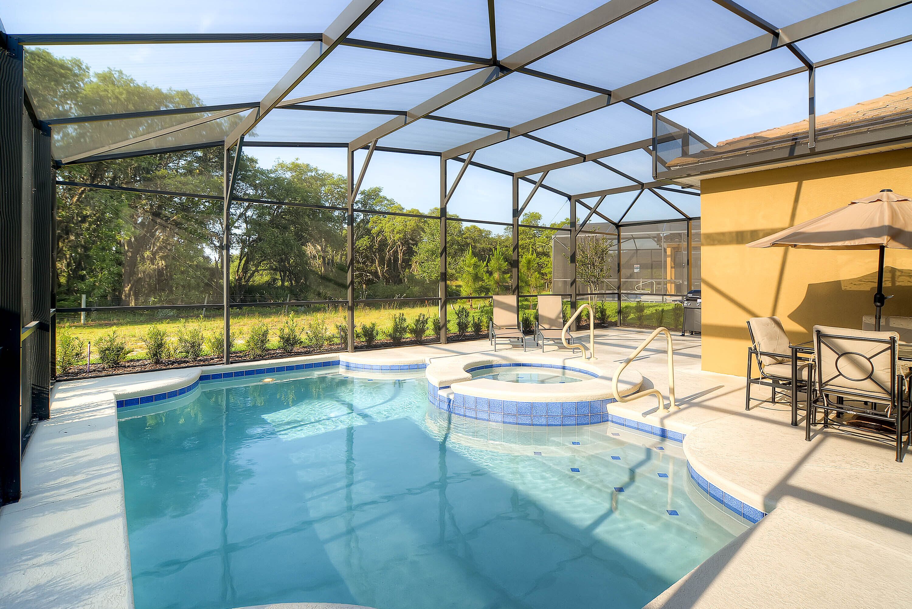 Piscina ao ar livre coberta com hidromassagem, rodeada por um terraço com cadeiras e um guarda-sol.