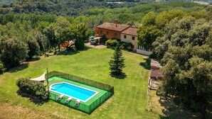 Una casa con piscina, rodeada por un patio cercado y árboles.