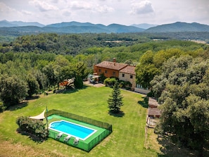 Una casa con piscina, rodeada por un patio cercado y árboles.