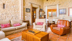 Un salón acogedor con paredes de piedra, una mesa de centro de madera con piezas de ajedrez y asientos cómodos.