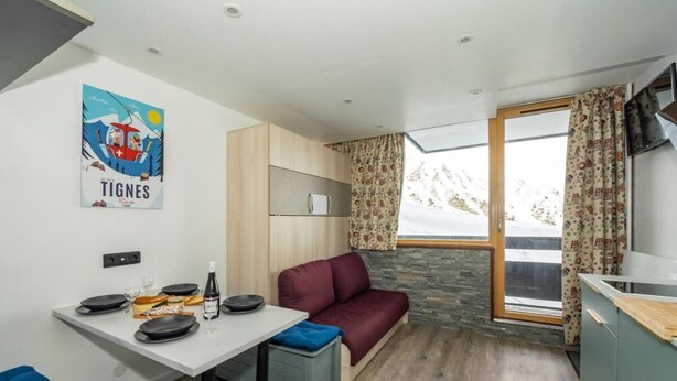 A compact living space with a dining area, a sofa, a kitchenette, and a large window with curtains. - 100m from resort center, Ground floor, balcony, tv, ski locker, 21m², Tignes (Tignes)