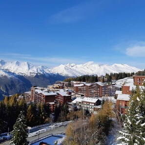 Un complejo turístico de montaña con varias edificaciones, incluyendo un hotel con balcones y una zona de piscina.