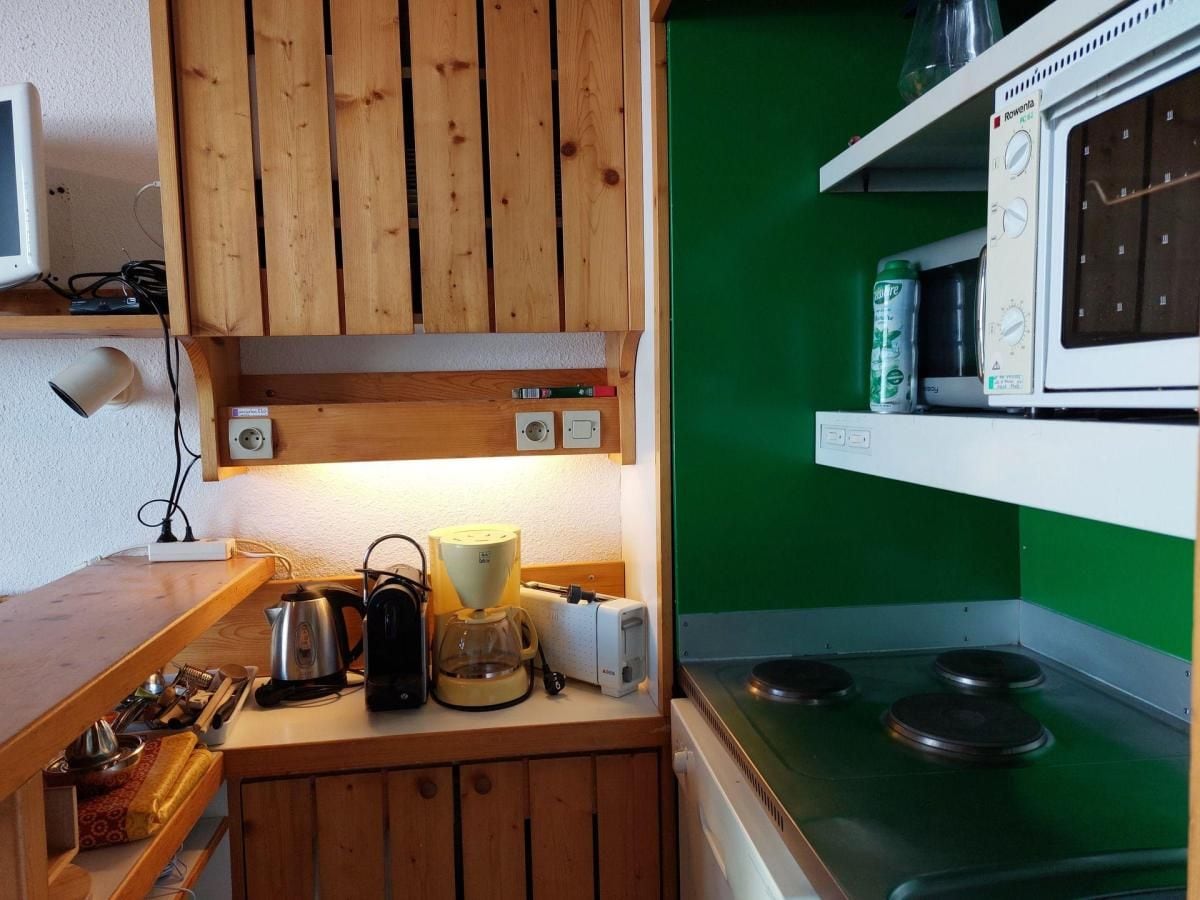 Ett kök med träskåp, en mikrovågsugn, en vattenkokare och en kaffebryggare.
