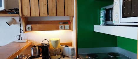 A kitchen with wooden cabinets, a microwave, a kettle, and a coffee maker.