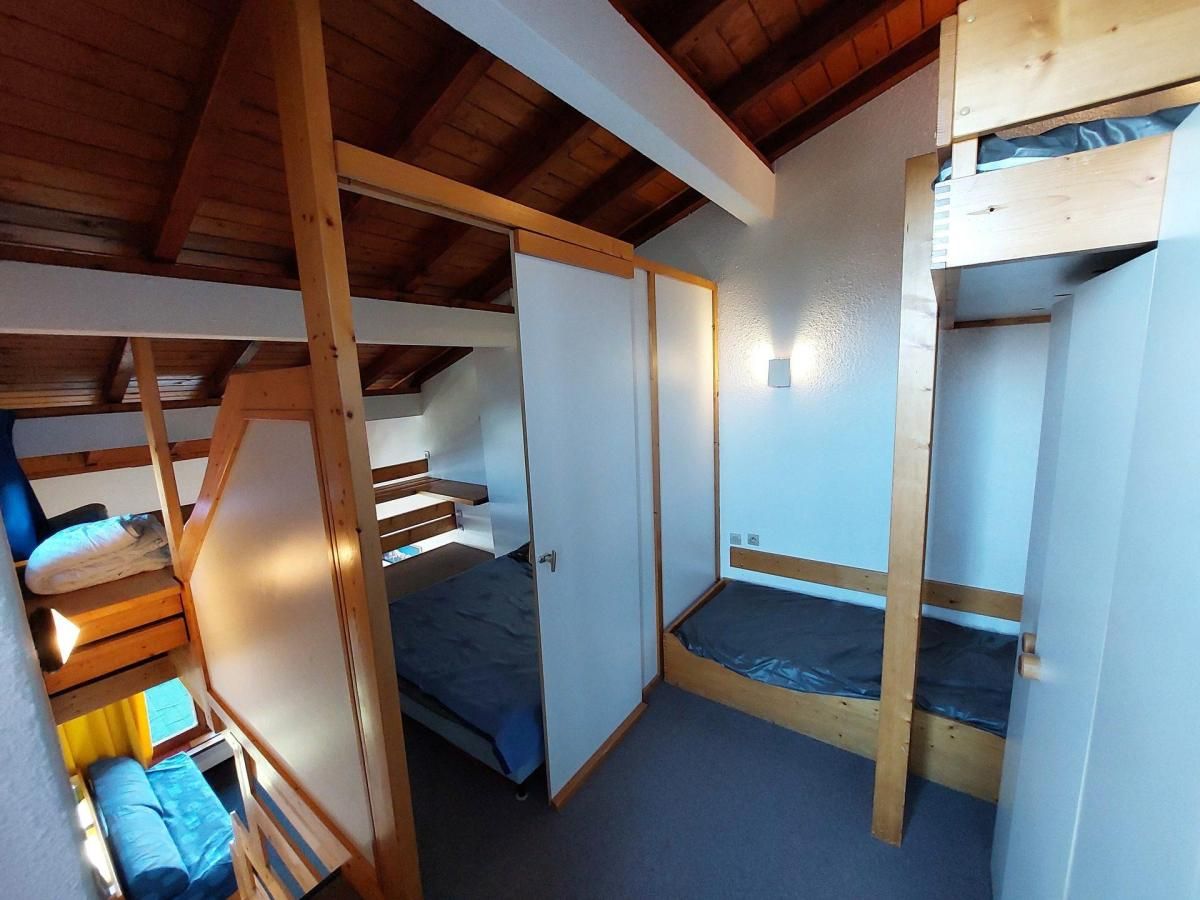 Una habitación pequeña con literas, una puerta y un ventanal.