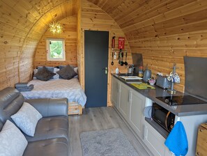 A cozy cabin interior with a bed, a sofa, a kitchenette, and a dining area. - Luxury Glamping Pod With Hot Tub, Fees Apply (Mablethorpe)