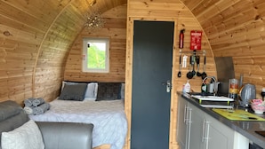 Ein gemütliches Blockhaus mit einem Bett, einer Couch, einer Küchenzeile und einem Fenster.