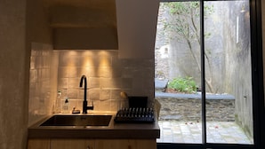 A modern kitchen with a large window, a built-in sink, and wooden cabinets.