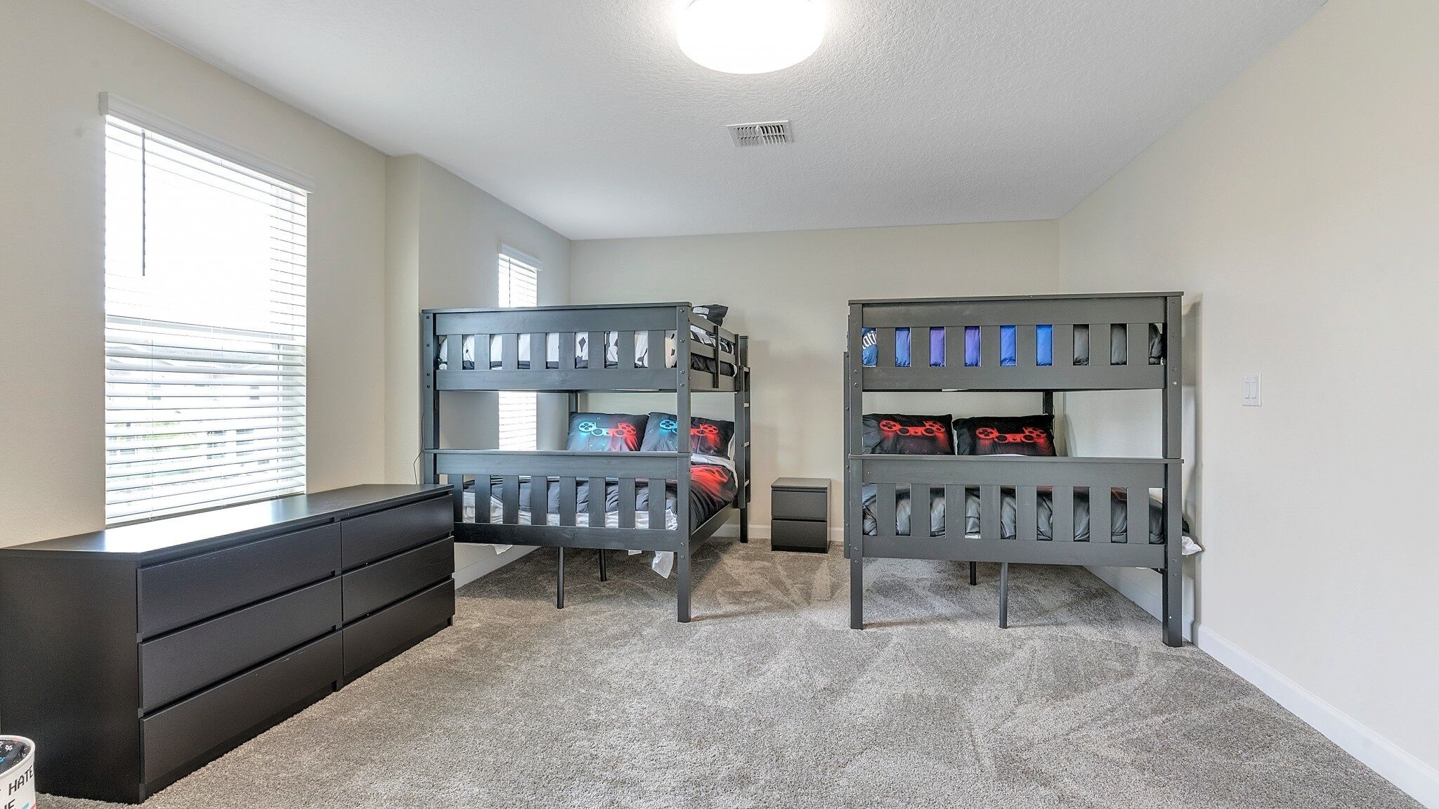 A room with two bunk beds, a dresser, and a window with blinds.