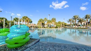 A swimming pool with inflatable rings, palm trees, and a clear sky. - 1233chd - The Retreat At Championsgate 9 Bedroom Home by RedAwning (Davenport)