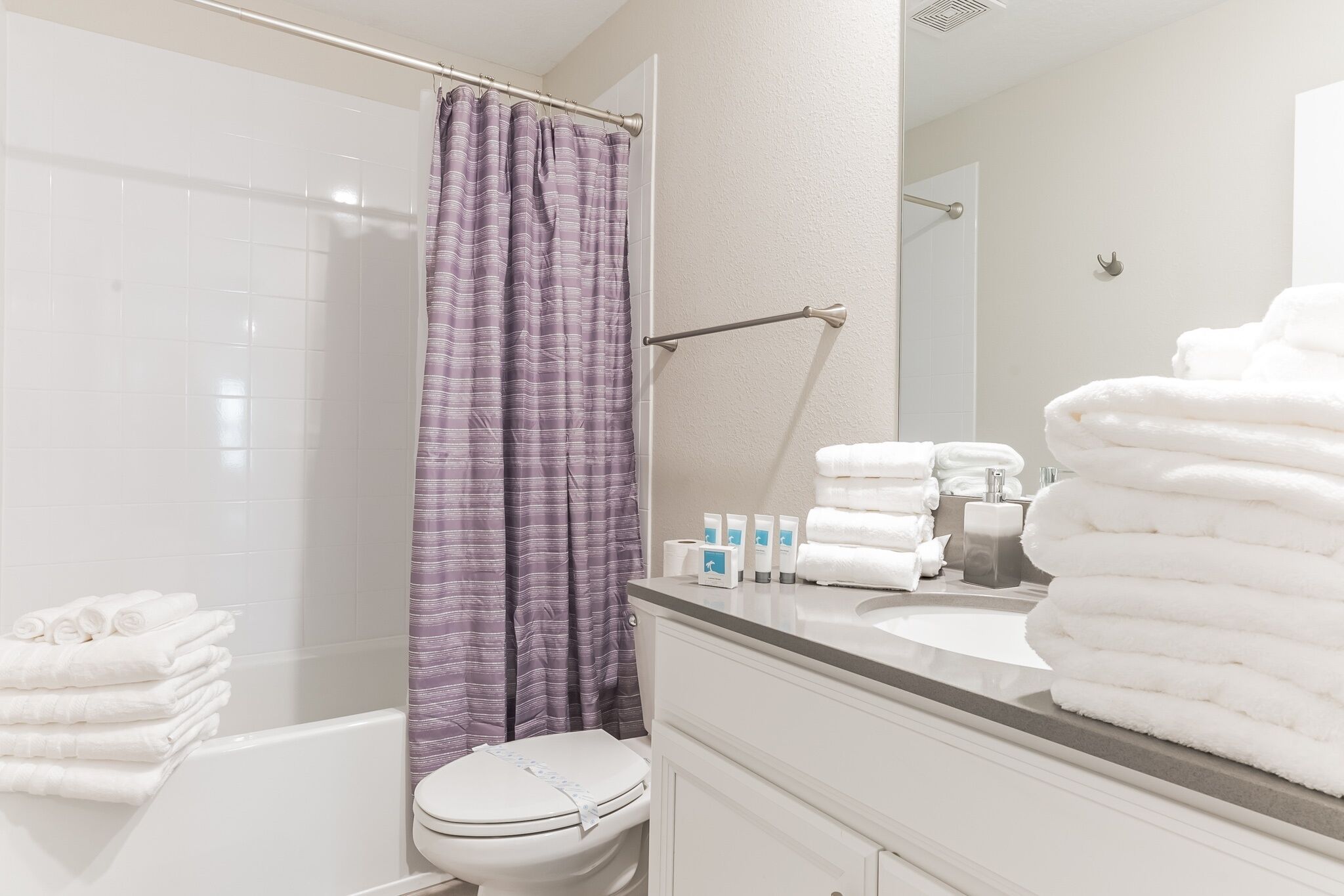 Een badkamer met douche, toilet en opgestapelde handdoeken.