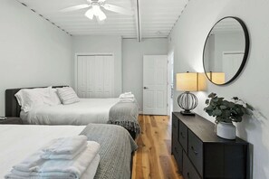 A bedroom with two beds, a ceiling fan, a dresser with a mirror, and a potted plant. - Modern Comfort Secluded Getaway Fish Creek Pines (Fish Creek)