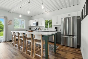A modern kitchen with a central island, stainless steel appliances, and wooden chairs. - Modern Comfort Secluded Getaway Fish Creek Pines (Fish Creek)