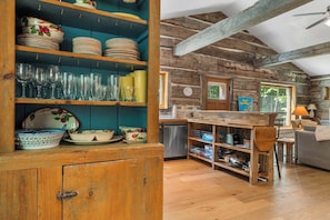 A rustic kitchen with wooden shelves, a dining area, and a clock on the wall.