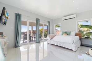 Ein modernes Schlafzimmer mit einem großen Bett, Schiebeglasüren zum Balkon und Blick ins Freie.
