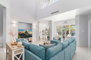A modern living room with a large sofa, a flat-screen TV, and a dining area. - Majestic 6BR Villa w/ Private Pool near Palm Beach (Noord)
