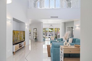 A modern living room with a flat-screen TV, a sofa, and a coffee table. - Majestic 6BR Villa w/ Private Pool near Palm Beach (Noord)